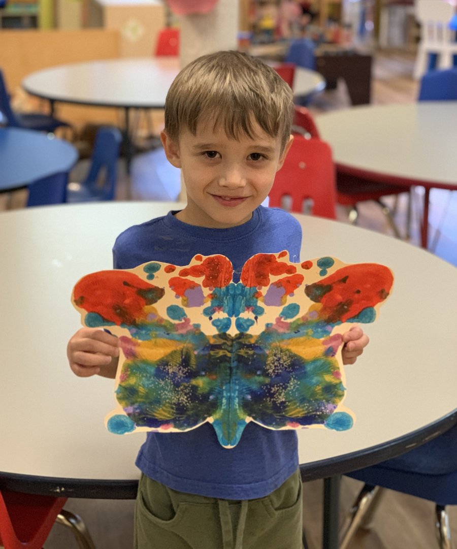 Child holding a butterfly-shaped painting at Butterflies Academy
